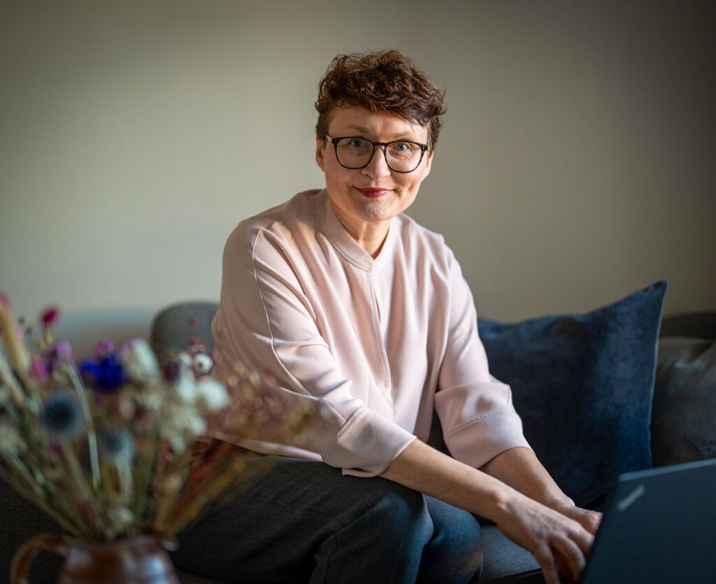 Tatjana Dellos sitzt auf einem Sofa und tippt in einen Laptop
